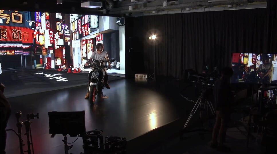 Актор на мотоциклі перед віртуальним екраном