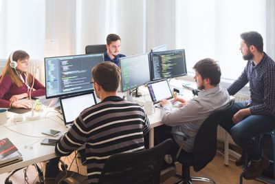 Команда розробників програмного забезпечення працює в офісі з великими моніторами