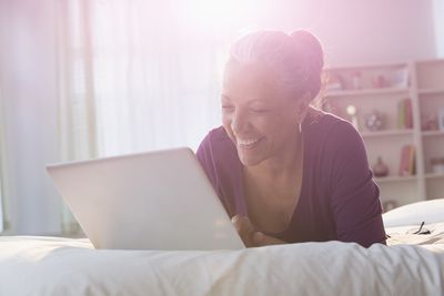 Жінка, використовуючи ноутбук на ліжку