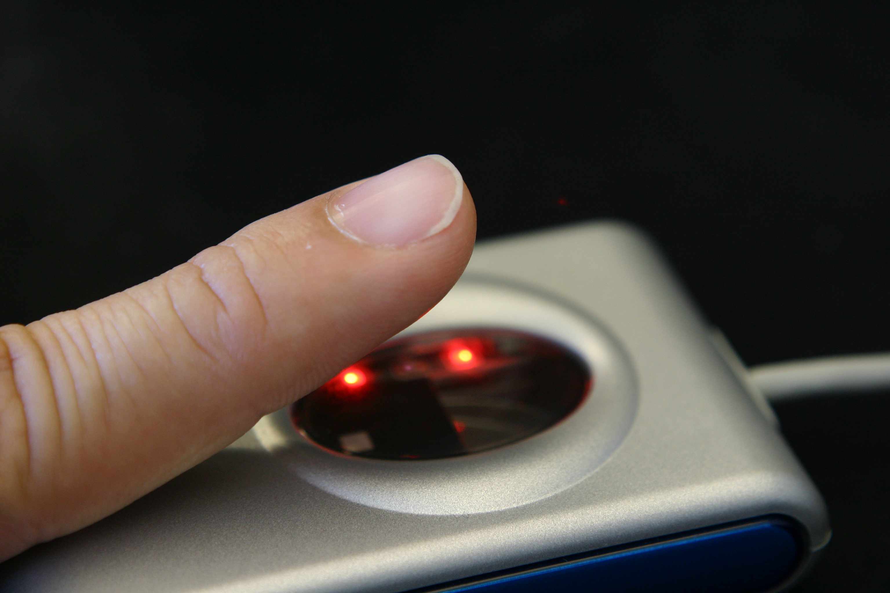 Крупним планом пальця на сканер відбитків пальців.