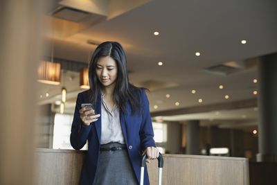 Бізнес-леді за допомогою смарт-телефону у фойє готелю