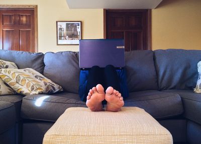 Босоніж за допомогою ноутбука на дивані